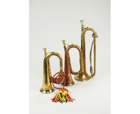 A copper and brass bugle, 27cm long, a brass bugle with decorative cord and tassel, 29cm long and a brass bugle, 40cm long al