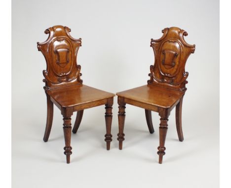 A pair of Victorian oak hall chairs, mid 19th century, each with shield back and c-scroll borders, tapering panel seat and ra