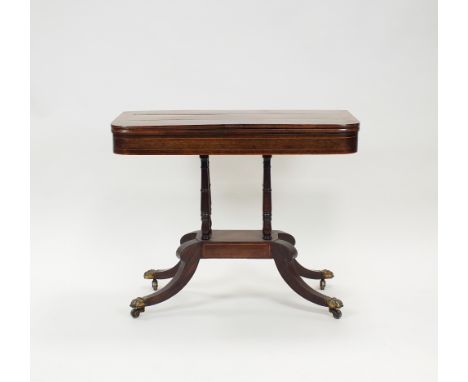 A Regency rosewood and boxwood strung fold-over top card table on four ring turned columns, platform base and hipped down cur