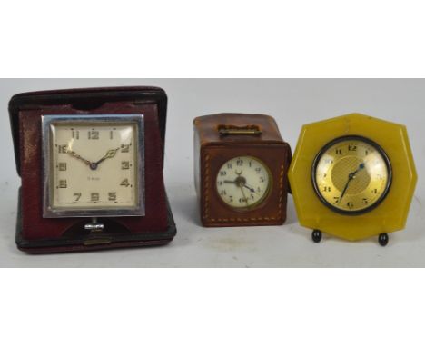 A leather cased small brass travelling timepiece with circular dial set with Arabic numerals, width 5cm, an eight day travell