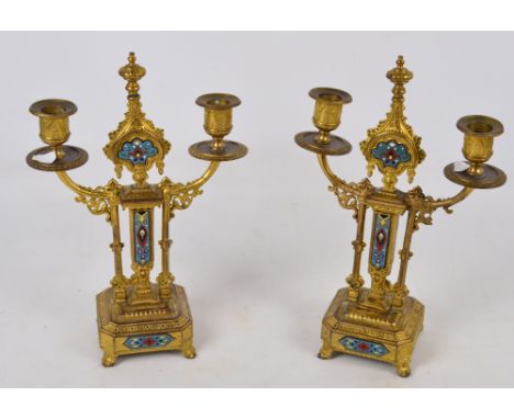 A pair of late 19th century gilt metal and enamel decorated two light candelabra, each with central turned finial flanked by 