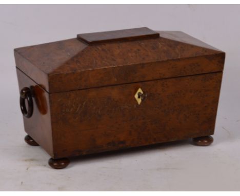An early Victorian burr yew wood sarcophagus tea caddy, the hinged lid enclosing two lidded compartments and central glass bo