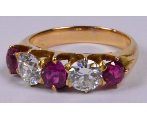 A yellow metal ruby and diamond five stone ring, the central pear shaped ruby flanked by twin diamonds, each weighing approx 