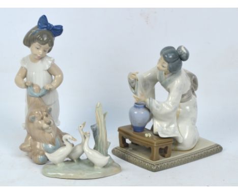 A Lladro figure of a seated Geisha arranging flowers (af), height 19cm and two Nao figures, one depicting a girl with a teddy