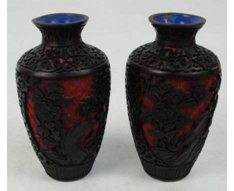 A pair of 20th century Chinese black and red lacquer baluster vases, decorated with peonies and chrysanthemum on scroll groun