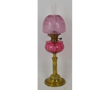 A Victorian brass oil lamp with cranberry glass reservoir and pink frosted glass floral decorated shade, height including fun