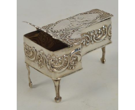 An Elizabeth hallmarked silver snuff/pill box in the form of a miniature grand piano, embossed with cherubic and scroll motif