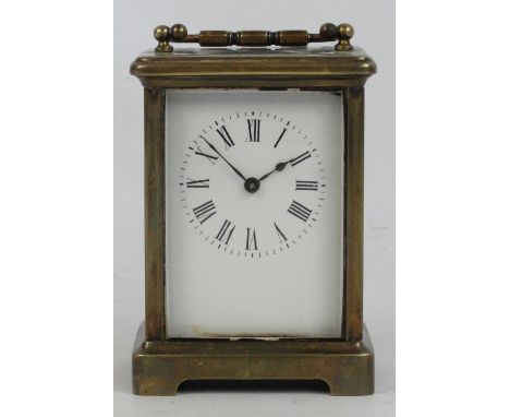 An early 20th century French brass carriage clock with swing loop handle above rectangular white enamel dial set with Roman n