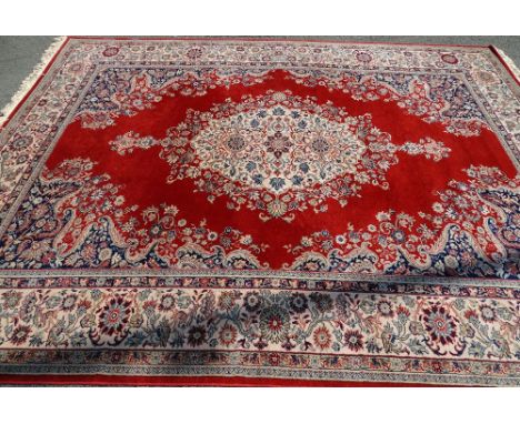 SUPER KESHAN RED GROUND CARPET classically patterned with tasselled ends, 275 x 365cms