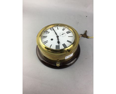 BRASS CASED SHIP'S CLOCK, mounted on oak, 22.5cm diameter