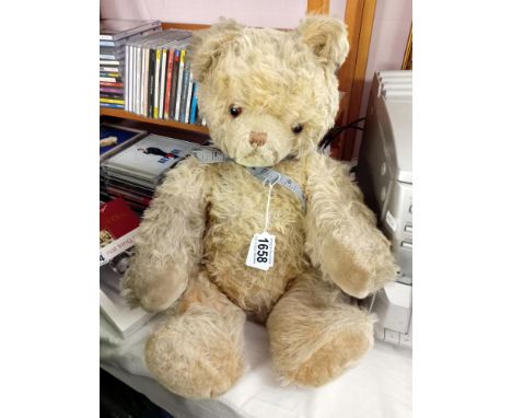 A vintage straw filled growler teddy in tired condition. No labels