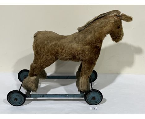 An early 20th century Chiltern Toys gold plush push-along horse. 19' high. Distressed.