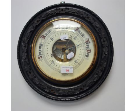 A 19TH CENTURY ANEROID BAROMETER in a carved and ebonised circular frame, 33cm dia.