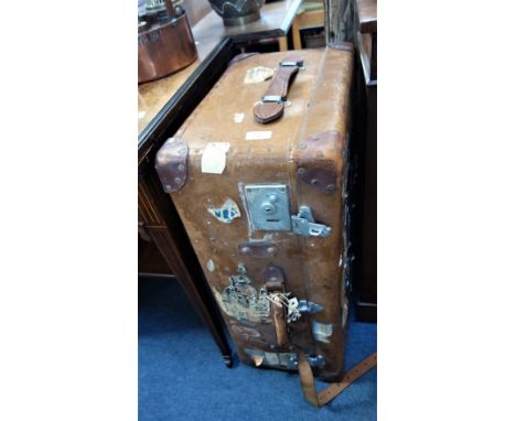 AN EARLY 20TH CENTURY TAN IMITATION LEATHER TRAVELLING TRUNK with leather carrying handles, labels include The Cunard Line an