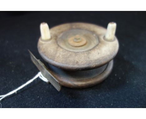 A VINTAGE WOODEN FISHING REEL with brass fittings
