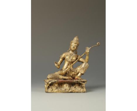 A THAI OR BURMESE GILT-BRONZE FIGURE, seated with one knee raised and playing a stringed instrument, 20th century, 16.5cm hig
