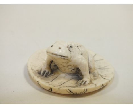 AN ORIENTAL CARVED BONE FIGURE OF A TOAD ON LILY PAD