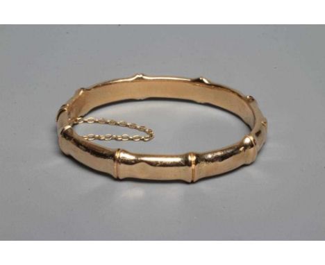 A LATE VICTORIAN FAUX BAMBOO STIFF HINGED BANGLE, unmarked, with safety chain (Est. plus 24% premium inc. VAT)Condition Repor