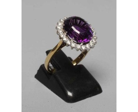 AN AMETHYST AND DIAMOND CLUSTER RING, the central oval facet cut amethyst claw set to a border of twenty two small brilliant 