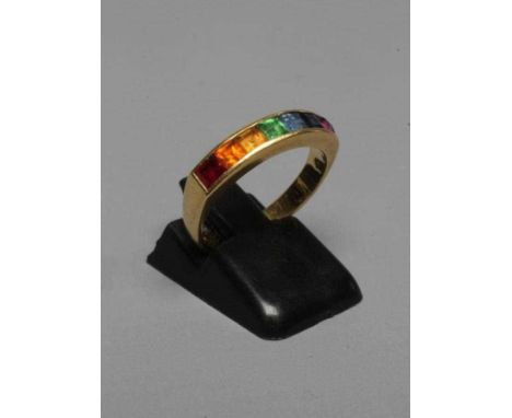 A MULTI-GEM HALF HOOP RING, the seven square cut stones including garnet, aquamarine and amethyst channel set to a plain 18ct