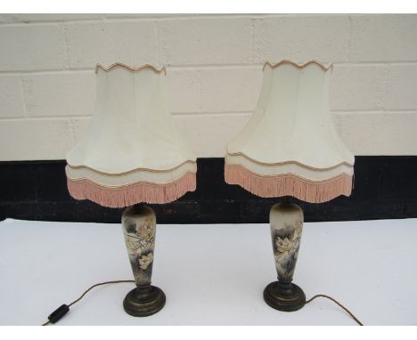 A pair of ceramic Art Nouveau lamps with floral decoration and tasselled shades, restoration to one lamp, 76cm tall
