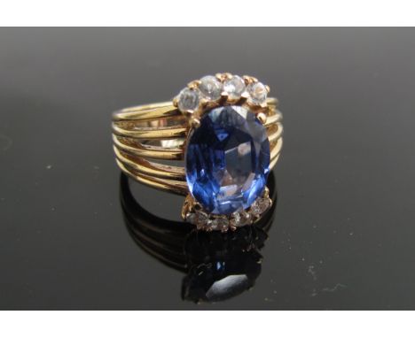 A gold ring with oval synthetic sapphire in multi split shoulders, stamped 9ct. Size K, 5g          