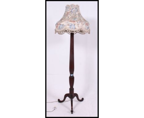 An early 20th century mahogany standard lamp with carved top above reeded column, above reeded lobed section to spreading tri