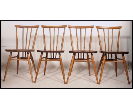 A set of 1970's retro Ercol beech and elm stick back dining chairs with panel seats raised on turned legs united by stretcher