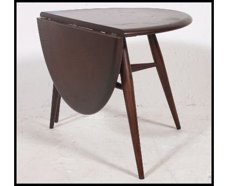 An Ercol retro 1970's drop leaf circular coffee - occasional table by Ercol raised on tapered legs with chamfered edge table 