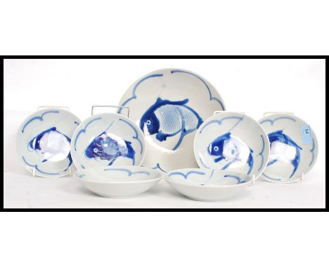 A collection of studio style blue and white ceramic Chinese bowls along with the serving bowl, each depicting a Carp to the c
