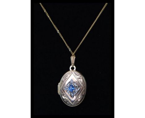 A 9ct gold ladies locket and 9ct gold necklace. The oval lozenge shaped locket with applied cornflower blue stone with cz sto