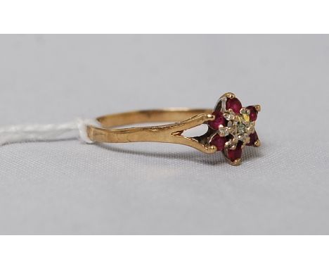 A 9ct gold diamond and ruby garnet stone flower ring. The illustion set diamond surrounded by 5 stones. Total weight 1.0g