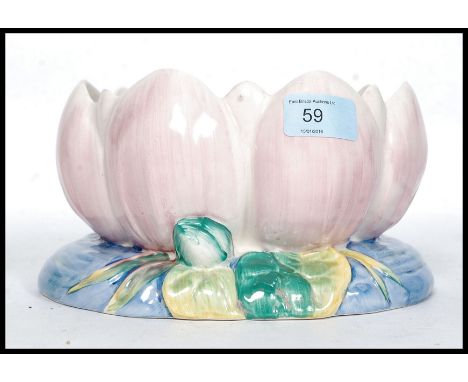 A Clarice Cliff bowl formed as a water lily decorated in pastel shades with pink leaves and blue base. Green Clarice Cliff st