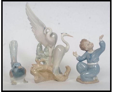 A Lladro figurine of a finch together with a Lladro small boy and a Nao figurine of storks. Tallest H26cm 