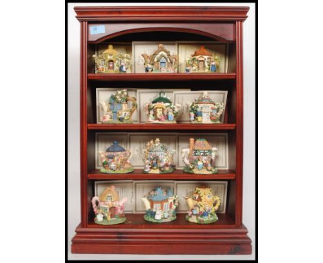 A collection of 12x Minerva Collection ceramic model cottage teapots, along with their display shelf. 