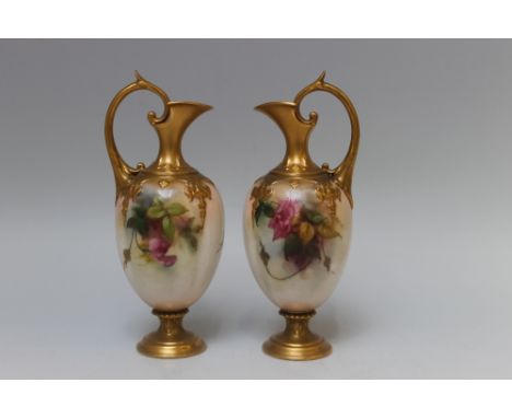 TWO ROYAL WORCESTER SMALL EWERS, signed E.M. Fildes, both with loop handles, floral painted and gilt decoration, puce mark to