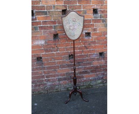 A 19TH CENTURY MAHOGANY POLE SCREEN, the shield shaped glazed screen with inset needlepoint tapestry, the turned stand raised