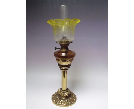 A BRASS REEDED COLUMN OIL LAMP, the circular base with embossed floral decoration, amber glass reservoir, citrus etched glass