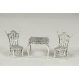 A miniature silver table and two chairs.