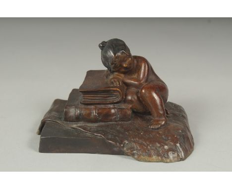 A small bronze of a girl sleeping on a pile of books, 10cm.
