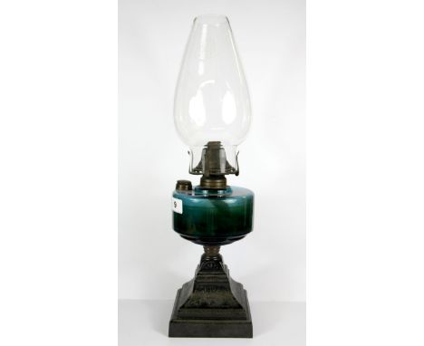 A Victorian oil lamp with cast iron base and green glass well, H. 50cm.