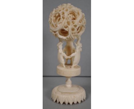 Carved ivory puzzle ball circa 1930 the multi layer ball supported by a pedestal base with 3 elephants, age crack to base, 14