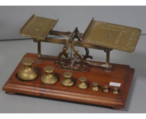 Vintage set brass postage scales on wood base, with 8 brass weights, from quarter ounce to 8 ounces, included. Length 24cm ap
