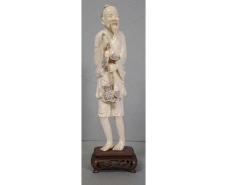 Chinese Republic (1912-1949) period ivory figure of a fisherman, on carved wooden stand, 22.9cm high (total.) This item may n