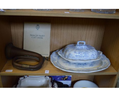 Blue and white vegetable dish with cover and similar plate, a copper bugle and the Princess Mary's gift book.