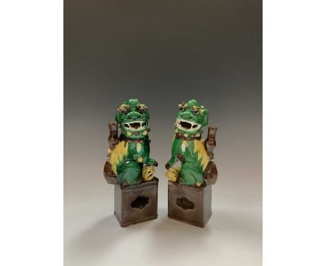 A pair of Chinese famille verte joss-stick holders, 19th century, each mounted with a dog of Fo seated on a rectangular plint