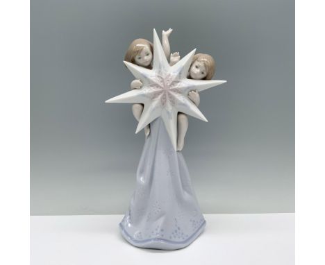 Two cherubs joyfully ride on a Christmas star, trailing a cloth beneath them. Lladro backstamp. This item has its original bo