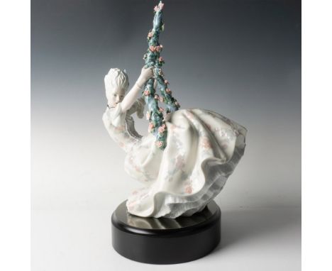 A glossy figure of a woman wearing an elaborate dress with ruffles and intricate floral pattern, and hair adorned with a feat