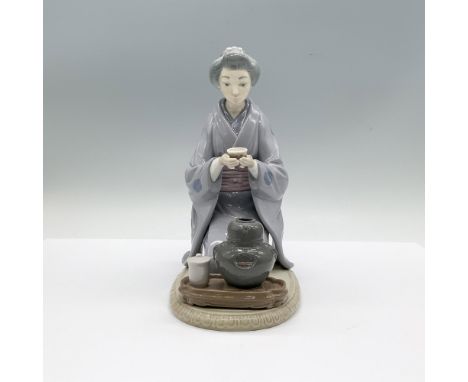 A glossy figure of woman dressed in a floral kimono, kneeling down as she enjoys a cup of tea. Lladro backstamp. This item ha