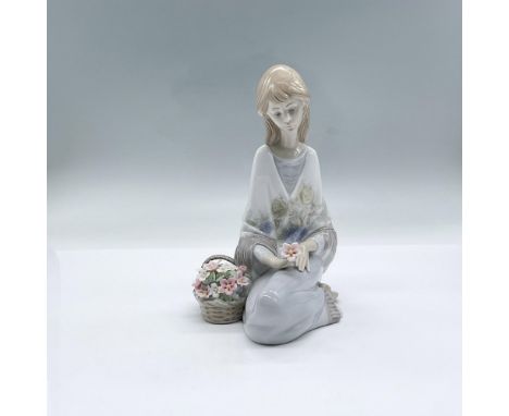 A glossy figure of a woman wearing a shawl with a delicate floral design, admiring a flower she is holding. 1998 Lladro Museu